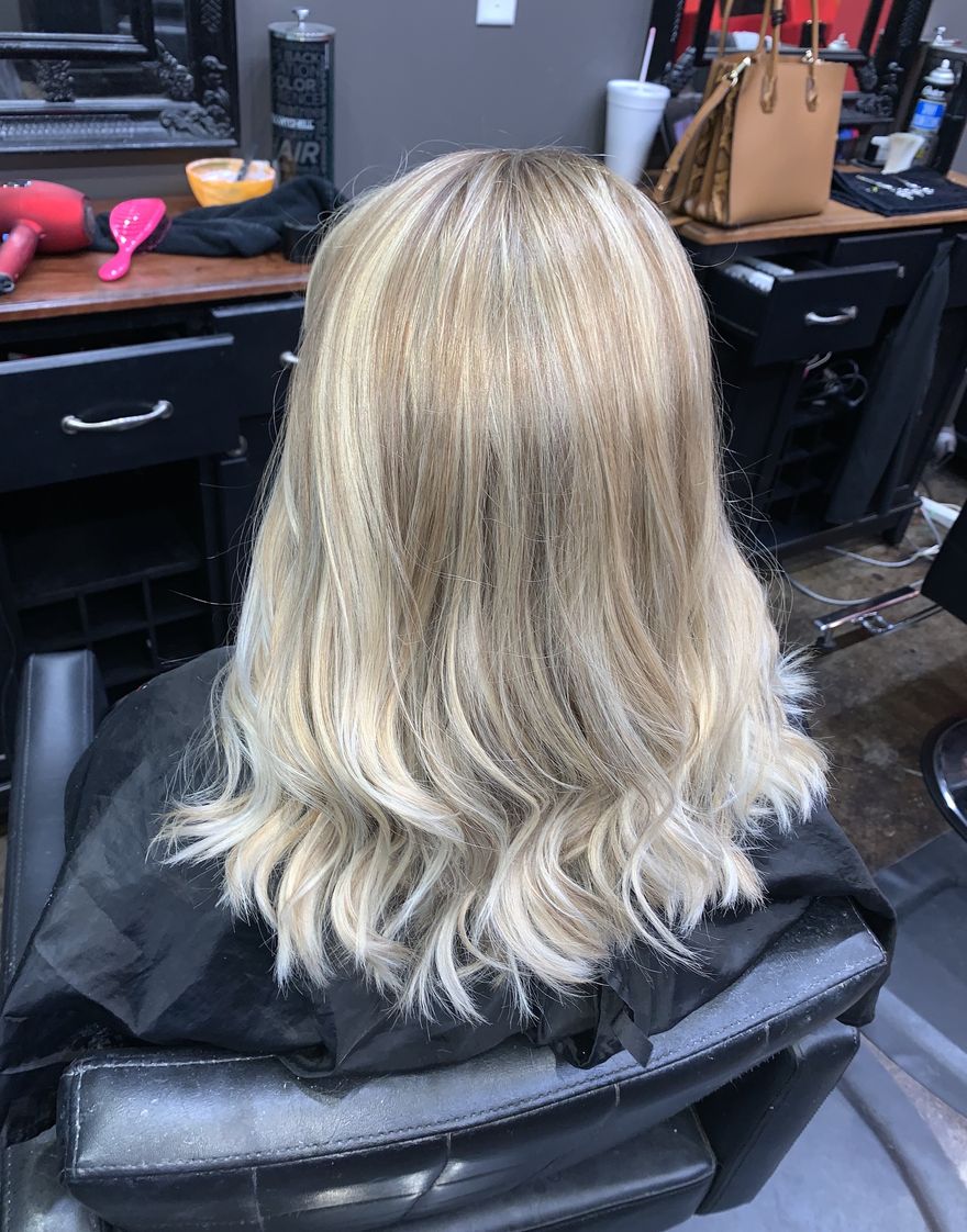 Long blonde highlights with soft waves, seen from the back in our salon chair